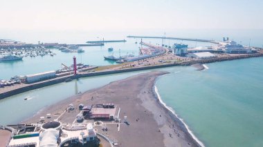 Yat körfezi olan bir pelerin. Şarjör. Yatlar için körfez ve turkuaz suyun arka planında deniz sanayisi olan güzel bir sahil. Yatları ve güneşli bir günde berrak turkuaz suları olan bir sahil.