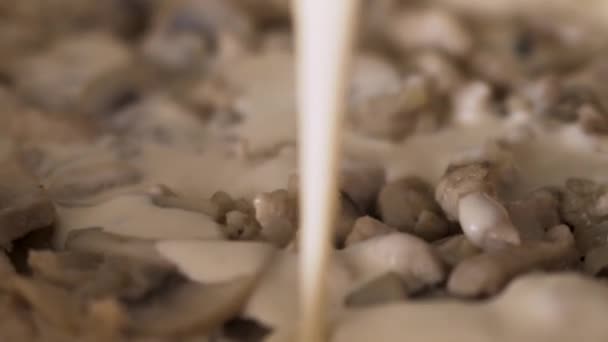 Close up de panela com cogumelos em um molho de creme. Acção. Nata grossa que está sendo derramada na panela com champinhons fritos, preparação de molho de cogumelos . — Vídeo de Stock