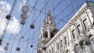 Arbat Caddesi 'ndeki sokak lambası süslemesi mavi bulutlu gökyüzü arka planı, Moskova, Rusya. Başla. Güzel çelenkler, beyaz tarihi bina ve bir kilise manzarası..
