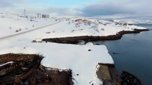 Aerial view of winter snowy sea coast with ruined boats after the shipwreck. Footage. Old sunken fishing boats on the shore of the Barents Sea. — Stock Video