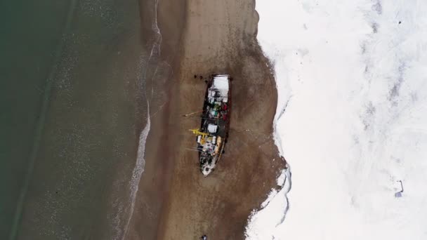 Widok na rozbity żaglowiec na Antarktydzie. Nagranie. Latanie nad zimowym, śnieżnym wybrzeżem nad morzem i starym zardzewiałym statkiem. — Wideo stockowe