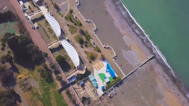 Vista superior de los turistas caminando a lo largo de la orilla del mar. Clip. Hermosa playa para vacacionistas cerca de aguas turquesas de mar. Hermosas olas de rollo de mar turquesa en la playa turística — Vídeo de stock