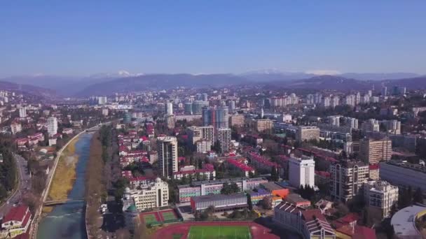 Vista superior de la ciudad desarrollada en el fondo del paisaje montañoso. Clip. Hermoso panorama de gran ciudad en valle sobre fondo de montañas — Vídeo de stock