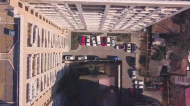 Bahçesinde park edilmiş arabalarla çok katlı bir binanın çatısının manzarası. Şarjör. Avlusu olan çok katlı binanın yatay üst görüntüsü