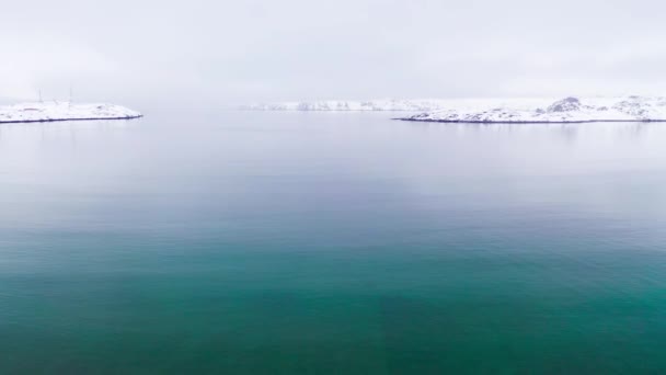 Ovanifrån av havet på bakgrunden av kusten på vintern. Fotografering. Vacker vinter panorama av lugnt blått hav på bakgrund av snöiga kusten — Stockvideo