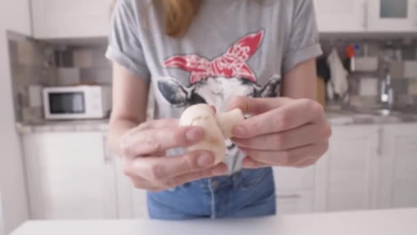 El primer plano de la mujer que prepara las setas para el plato. Acción. Mujer joven desenrosca tapas de setas de las piernas y los pone en tablero de madera — Vídeos de Stock