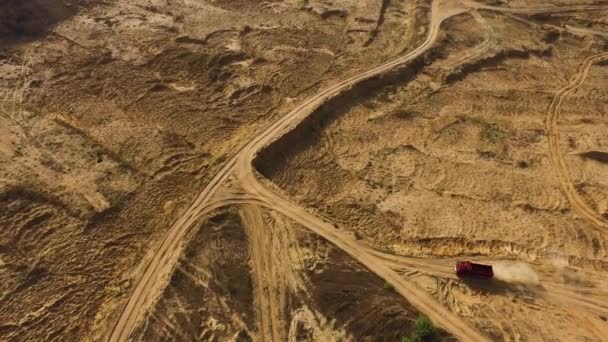 Aerial of dump truck driving on rural dusty road, transportation concept. Scene. Top view of truck moving on a dirty path in countryside area on a summer day. — Stock Video