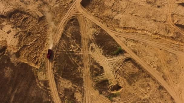 Blick von oben auf staubige Sandpiste mit Radspuren und rotem LKW. Szene. LKW bewegt sich und hinterlässt eine staubige Spur in der Luft, schwere Räder, Maschinenkonzept. — Stockvideo