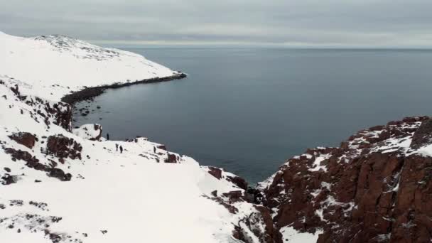 Vista aérea da Noruega e costa nevada perto do mar na temporada de inverno, na Europa. Filmagem. Montanhas brancas nevadas, paisagem natural de rochas cobertas de neve e mar frio calmo . — Vídeo de Stock
