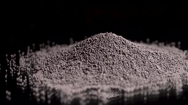 Close up of black pepper pile lying on the black surface and on a black background, cooking food and spices concept. Stock footage. Black pepper corns, small grains. — Stock Video