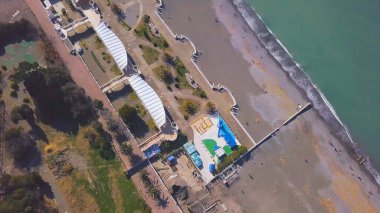 Deniz kıyısında yürüyen turistlerin en iyi görüntüsü. Şarjör. Turkuaz deniz suyu yakınında tatil yapanlar için güzel bir sahil. Turistik plajda güzel turkuaz dalgalar.