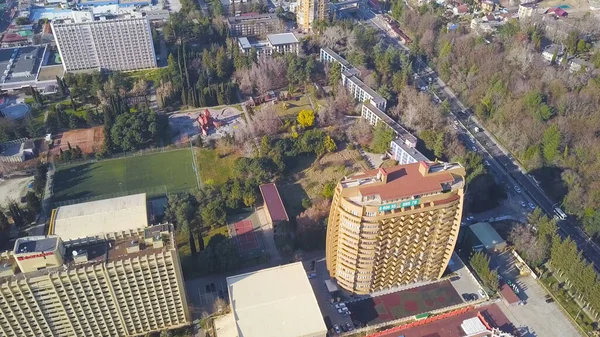 Vista dall'alto di case e alberghi situati sulla costa del mare. Clip. Città turistica con alberghi vicino al bordo del mare nella soleggiata giornata estiva. Edifici a più piani con parchi giochi sullo sfondo del mare — Foto Stock