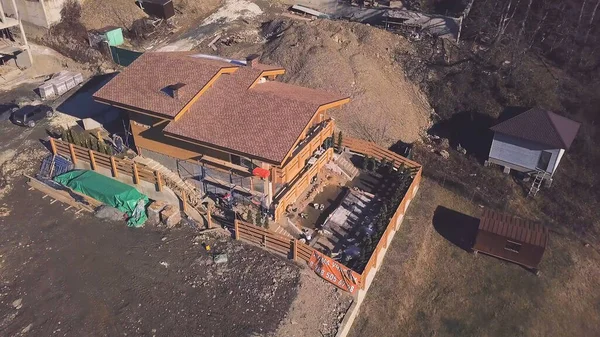 Top view of cottage under construction in country. Clip. Buildings in suburbs of private houses. Construction of private cottage on outskirts of city near forest