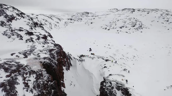 Blick von oben auf eine Gruppe von Menschen im Winter auf dem Pass. Verfilmung. Panorama von Touristen, die im Winter zwischen Gebirgsfelsen reisen — Stockfoto