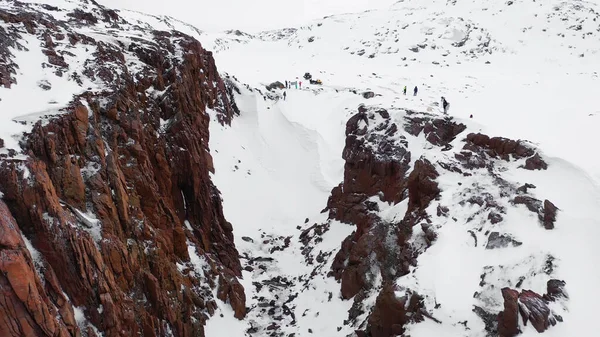 Blick von oben auf eine Gruppe von Menschen im Winter auf dem Pass. Verfilmung. Panorama von Touristen, die im Winter zwischen Gebirgsfelsen reisen — Stockfoto
