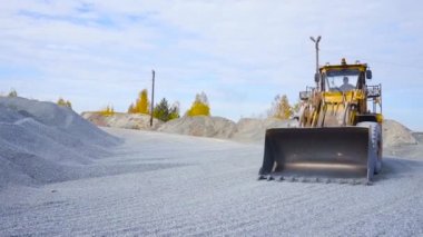 İnşaat alanındaki traktör moloz taşıyor. Stok görüntüleri. Traktör inşaat alanında ya da madencilikte çalışıyor. Yığından moloz toplayan sarı traktör