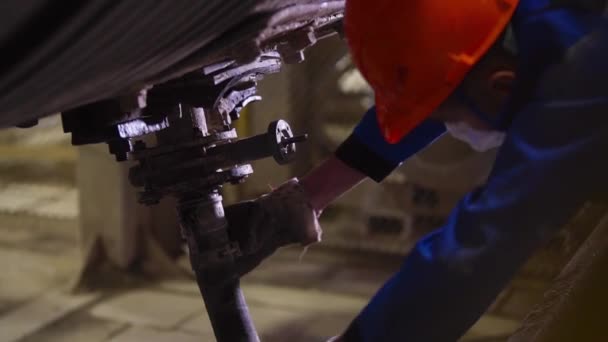 工人们在工厂解开软管螺丝.库存录像。工厂的专业工人在储气罐下监测设备和拧松软管 — 图库视频影像