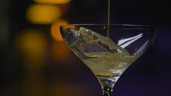 Κοντινό πλάνο σε διάφανο ποτήρι με πάγο ρίξτε λαμπερό ποτό. Στικ. Παχύ ιριδίζον αλκοολούχο ποτό χύνεται στο ποτήρι Martini με πάγο — Φωτογραφία Αρχείου