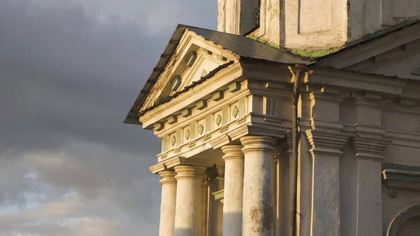Pediment boven zuilen van oud gebouw. Voorraadbeelden. Prachtige gevel van oud gebouw met zuilen in zonlicht op achtergrond van bewolkte lucht — Stockfoto