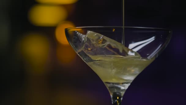 Şeffaf bardakta buzlu, parlak içecekle yakın plan. Stok görüntüleri. Kalın yanardöner alkolik içeceği buzlu Martini bardağına dökülüyor. — Stok video