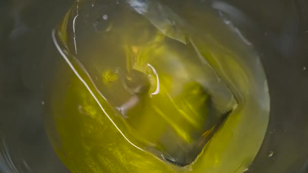 Detailní záběr v průhledném skle s ledem nalít lesklý nápoj. Záběry ze skladu. Tlustý alkoholický nápoj je nalit do Martini sklenice s ledem — Stock video