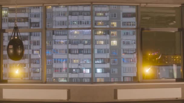 Widok panoramiczny z okna sąsiedniego domu. Materiał filmowy. Widok od wewnątrz pusty apartament z migającym światłem neonowym na tle okien sąsiedniego budynku — Wideo stockowe