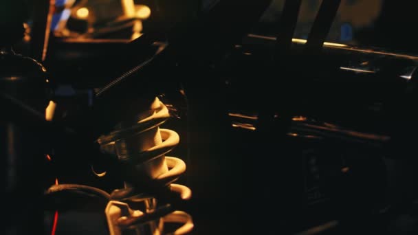 Detalhes de close-up do motor do carro no fundo da luz brilhante. Imagens de stock. Luz amarela ilumina formas escuras de peças com molas e cilindros para carro — Vídeo de Stock