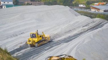 Traktör moloz yığınının üzerinde. Stok görüntüleri. Traktör yükleyicisi enkaz yığınının üzerindeki yolu temizliyor. Ağır taşımacılık ile yıkıntı madenciliği veya inşaat işi