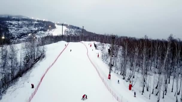 Top view of ski resort in cloudy weather. Stock footage. Beautiful snowy mountains with forests and ski trails on background of fog and overcast winter sky — Stock Video