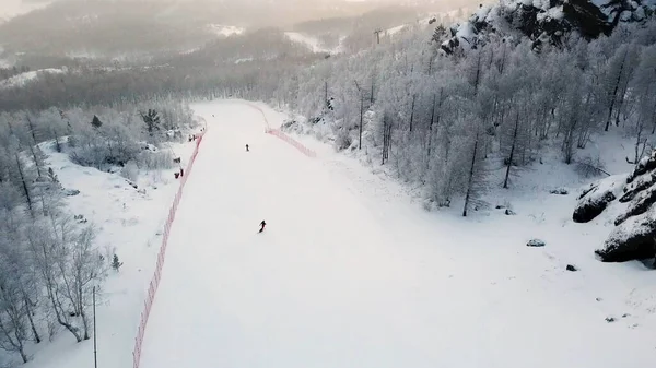 Vista aerea della stazione sciistica e montagne innevate coperte da foresta di conifere. Filmati delle scorte. Pista bianca con piste da sci e snowboard, sport e natura . — Foto Stock