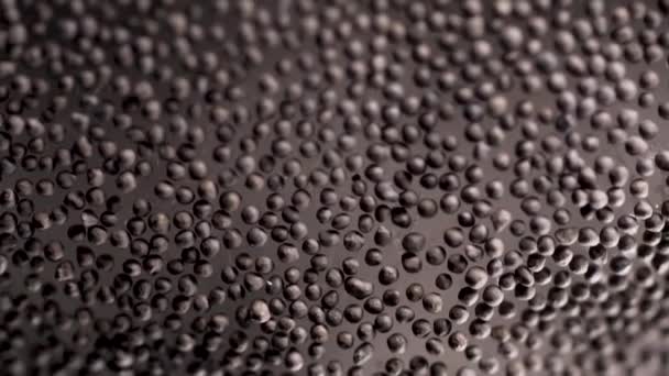Black peppercorn background, grains lying on glass surface. Stock footage. Close up of black pepper seeds as texture, organic food, healthy lifestyle and diet concept. — Stock Video