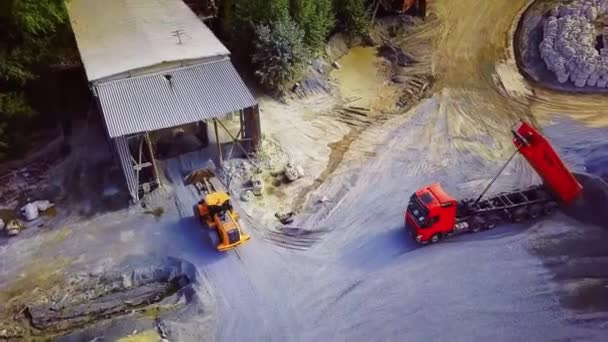 Lavori di scavo per l'estrazione di pietra frantumata. Filmati delle scorte. Vista dall'alto della pala caricatrice del trattore che trasporta pietre o ciottoli frantumati al magazzino — Video Stock