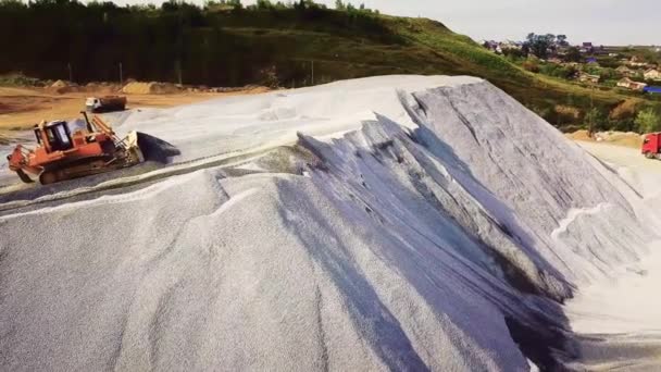 Ovanifrån av spillrorna gruvdrift. Lagerbilder. Brytning av grus eller småsten med tung transport på bakgrunden av byn på sommaren — Stockvideo