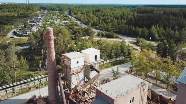 마을 배경에 벽돌 굴뚝 이 있는 공장. 자료 화면이요. 여름에 푸른 숲 이 있는 마을의 배경에 굴뚝 이 있는 벽돌 공장의 꼭대기 사진 — 비디오