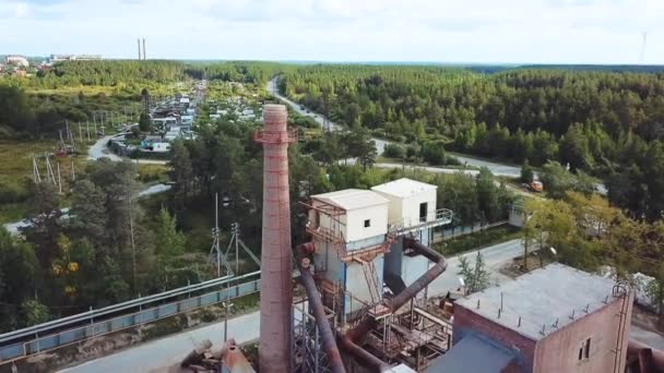마을 배경에 벽돌 굴뚝 이 있는 공장. 자료 화면이요. 여름에 푸른 숲 이 있는 마을의 배경에 굴뚝 이 있는 벽돌 공장의 꼭대기 사진 — 비디오