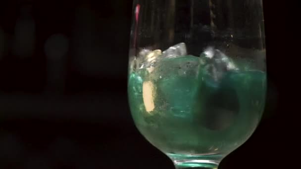 Primo piano della bevanda alcolica che viene mescolata al rallentatore. Filmati delle scorte. Cucchiaio mescolando verde coctail insolito con ghiaccio isolato su sfondo nero . — Video Stock