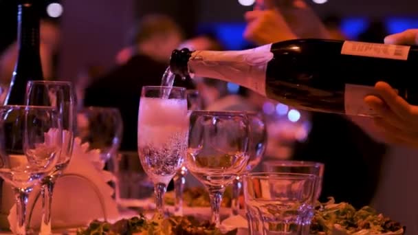 Bardaki ya da restorandaki bardağa şampanya döken bir elin yakın çekimi. Stok görüntüleri. Partide alkol geçmişi, kutlama konsepti. — Stok video