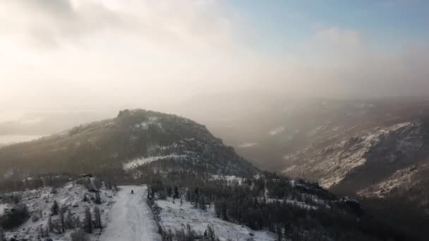공중에서 스키 리조트와 울창 한 밀림으로 덮여 있는 눈덮인 산들을 볼 수있다. 자료 화면이요. 구름낀 하늘 배경에 스키 트랙 이 있는 하얀 언덕 경사면, 스포츠와 자연 개념. — 비디오