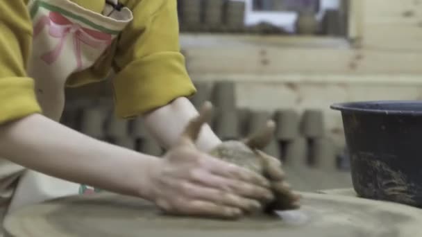 La clase maestra sobre el modelado de la arcilla sobre la rueda de alfarero En el taller de cerámica. Imágenes de archivo. Primer plano de las manos de mujer creando algo a partir de la arcilla . — Vídeo de stock