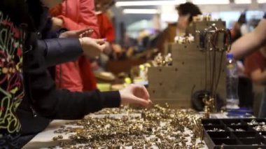 Farklı heykeller ve hediyelerle hediyelik eşya pazarı. Stok görüntüleri. Masada bir sürü altın figürle duran ve onları sokak pazarından seçen insanların yan görüntüsü..