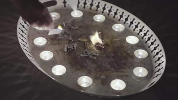 Magic ritual of burning paper with candles. Stock footage. Close up of divinations before Christmas, women hands burning small pieces of paper on the metal tray, traditions and superstitions concept. — Stock Video