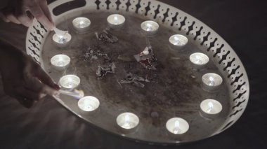 Magic ritual of burning paper with candles. Stock footage. Close up of divinations before Christmas, women hands burning small pieces of paper on the metal tray, traditions and superstitions concept. clipart