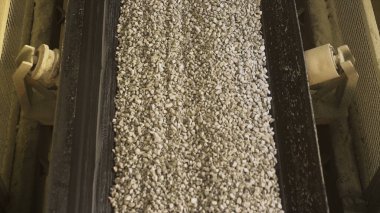 Close up of conveyor belt with gravel. Stock footage. Many small crushed stones on the production line at the construction materials production factory, heavy industry concept. clipart