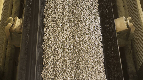 Close up of conveyor belt with gravel. Stock footage. Many small crushed stones on the production line at the construction materials production factory, heavy industry concept.