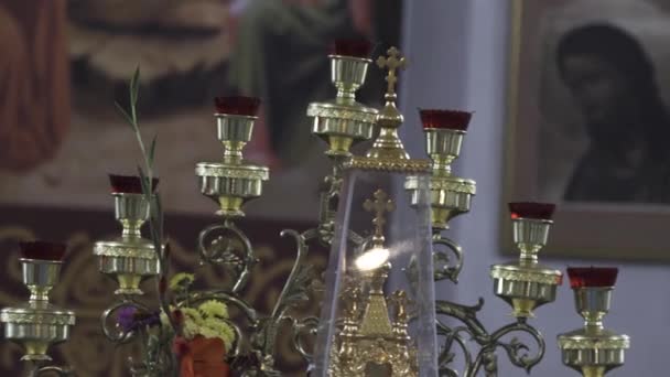 Gros plan d'une vieille menorah à l'église. Images d'archives. Détails de l'intérieur du temple orthodoxe, beau chandelier avec une croix et des fleurs sur fond d'icônes floues . — Video