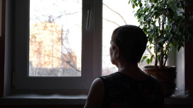 Büyükannemin pencereden dışarı bakışı. Kavram. Yaşlı kadın pencereden dışarı bakar ve birini görmeyi bekler. Yaşlı kadın sokakta olanlara bakıyor.