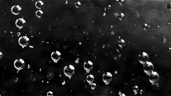 Belles bulles transparentes dans l'eau se déplaçant lentement. Images d'archives. Gros plan de nombreuses bulles d'air qui coulent sous l'eau et certaines d'entre elles s'élèvent sur fond noir, monochrome . — Photo