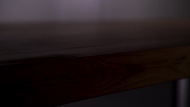 Trätabell på svart bakgrund. Lagerbilder. Närbild av trä bordsskiva polerad lysande yta i mörkret som förändras av ljuset. — Stockvideo