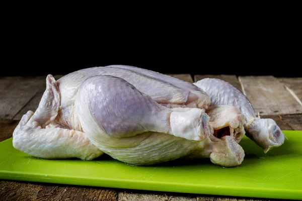 Frango cru em uma tábua de madeira em uma cozinha antiga — Fotografia de Stock