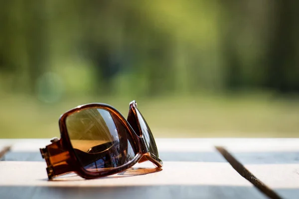 Sunglasses on the table in the sun on a wooden table — Stock Photo, Image